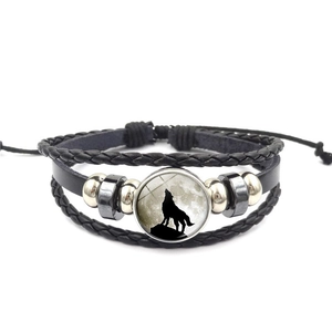 Makroaufnahme eines Lederarmbands mit einsamem Wolf-Edelstein-Anhänger und Metallperlen