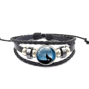 Detail eines mehrlagigen Lederarmbands mit Wolf-Mond-Glasstein und geflochtenen Schnüren
