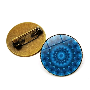 Detalle de broche de cristal mandala vintage con base de bronce y cierre de seguridad