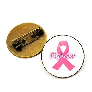 Détail de la broche ruban rose montrant le dôme en verre et l'épingle en bronze au dos