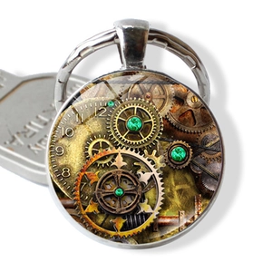 Macro detail of steampunk gear pattern keychain with emerald green accents in silver frame