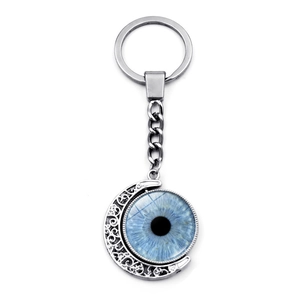 Detail of silver hollow moon keychain with blue evil eye pendant and intricate vine patterns