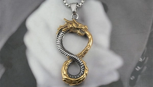 Detailed close-up of a dual-tone dragon pendant showing fine scales and infinity structure