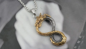 Macro shot of gold and silver infinity dragon pendant with detailed scales on a box chain