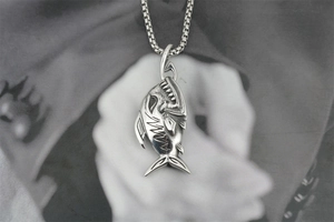 Gros plan d'un pendentif en forme d'os de poisson en acier titane avec finition vintage