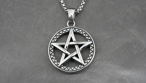 Vue macro du pendentif pentagramme viking avec textures géométriques sur chaîne box