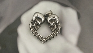 Vue macro du pendentif cœur gothique argenté avec deux crânes et texture métal vintage