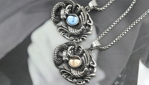 Détail de pendentifs dragon et phénix argentés vintage avec pierre bleue et chaîne