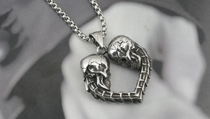 Détail d'un pendentif cœur avec crânes gothiques et chaîne à boîte en argent vintage