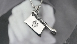 Détail d'un pendentif en forme de couteau en acier titane avec gravure kanji et chaîne