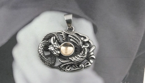 Détail du pendentif dragon en acier titane avec gravure creuse et perle dorée