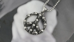 Detail of vintage silver peace sign pendant with skull textures on a thick box chain link
