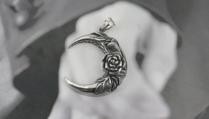 Detailed view of crescent moon pendant with rose engraving and vintage silver finish