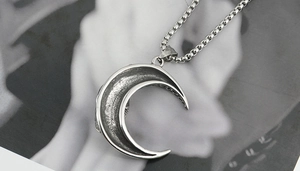 Detail showing vintage silver moon pendant with aged finish and box chain on minimalist magazine