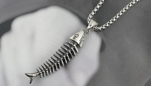 Close-up of punk style silver fish bone pendant with engraved S. Steel detail on box chain