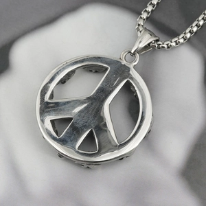 Polished silver peace sign pendant necklace with a box chain on white marble surface