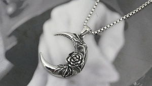 Macro shot of silver crescent moon necklace with intricate rose engraving and box chain