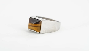 Detailaufnahme eines Herrenrings aus Edelstahl mit rechteckigem Tigerauge-Edelstein-Inlay