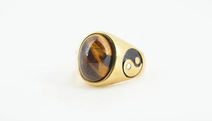 Macro shot of gold vintage ring featuring oval tiger eye stone and yin yang side detail