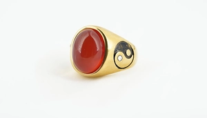 Detail of vintage gold ring featuring red oval gemstone and yin yang side engraving