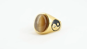 Macro detail of gold-tone Tai Chi ring with oval tiger eye stone and small zircon inlay