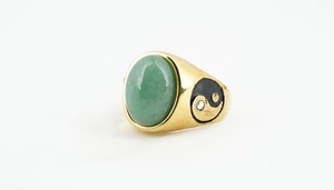 Detailed side view of a gold wide band ring with a green gemstone and Yin Yang pattern