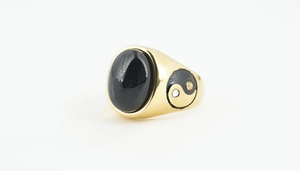 Macro detail of gold vintage ring with black oval onyx stone and Yin Yang side carving