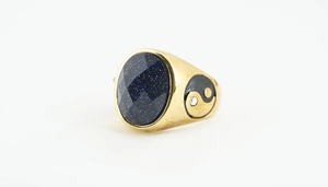 Macro detail of vintage gold ring with blue sandstone and yin yang engraving