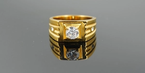 Macro shot of gold wide band ring with three inset diamonds on black mirror surface