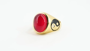 Macro detail of gold-tone ring featuring a large red oval stone and Tai Chi engravings