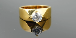 Macro shot of men's wide gold titanium ring featuring a round cut crystal in 4-prong setting