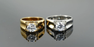 Dettaglio degli anelli di coppia in oro e argento con zircone tondo e montatura a quattro griffe