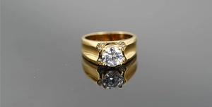 Dettaglio di un anello in titanio dorato con grande pietra centrale tonda e piccoli cristalli