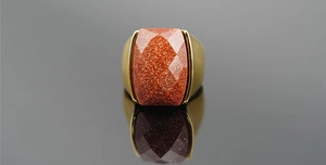 Detailed top view of a gold-tone ring featuring a rectangular goldstone with metallic sparkles