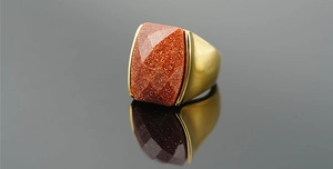 Macro shot of rectangular red sandstone gemstone in gold steel vintage ring