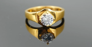 Detailed close-up of a golden hexagonal ring setting with a brilliant round center stone