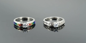 Detail of silver rings with round cubic zirconia and rainbow square side stones