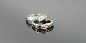 Detail view of silver rings with rainbow gradient stones and a classic round diamond