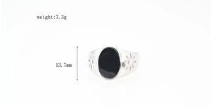 Macro detail of men's vintage steel ring with black gemstone and engraved side patterns