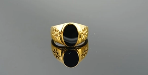 Macro shot of gold-plated signet ring with oval black onyx and sunburst engraving