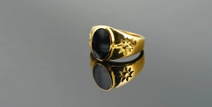 Detail of vintage gold-toned titanium ring with oval black onyx and starburst engraving