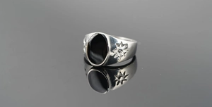 Detail of vintage steel ring featuring an oval black gemstone and star engravings