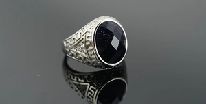 Detail of vintage blue sandstone ring with Greek meander patterns and side zircon accents