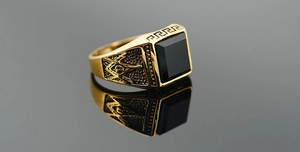 Macro shot of gold Masonic signet ring with square black stone and G compass engraving