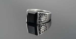 Close-up of men's stainless steel ring with black gemstone and geometric cutout detail