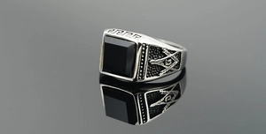 Macro detail of men's Masonic ring with square black obsidian stone and silver steel finish