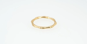 Detailed close-up of golden bamboo-joint style ring for men and women on white background