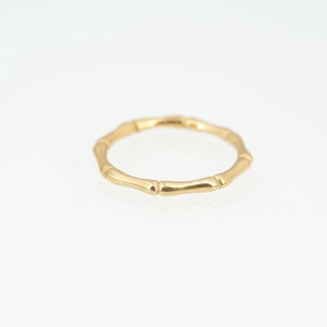 Gold bamboo-shaped stainless steel ring with natural texture on a white background