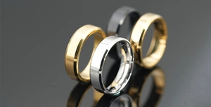 Close-up of four brushed titanium steel rings in gold silver black and rose gold finishes