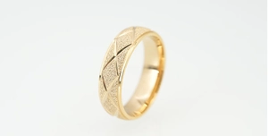 Detailansicht eines goldenen Rings mit Rautenmuster und sandgestrahlter Oberfläche